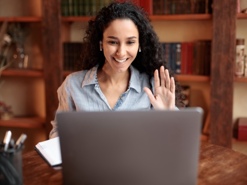 woman waving at computer screen 