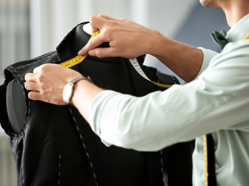 man tailoring fabrics on mannequin